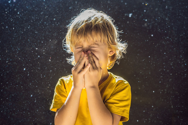 boy sneezing due to indoor air pollution.