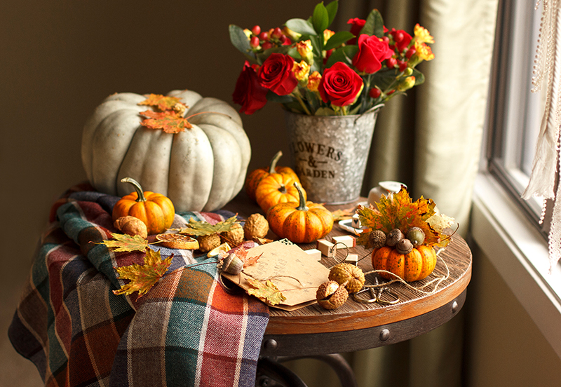 Indoor table decorated with pumpkins, acorns, chestnuts, and flowers.