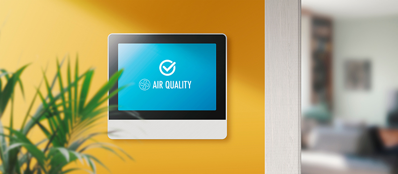 Air quality monitor mounted on the wall of a home.
