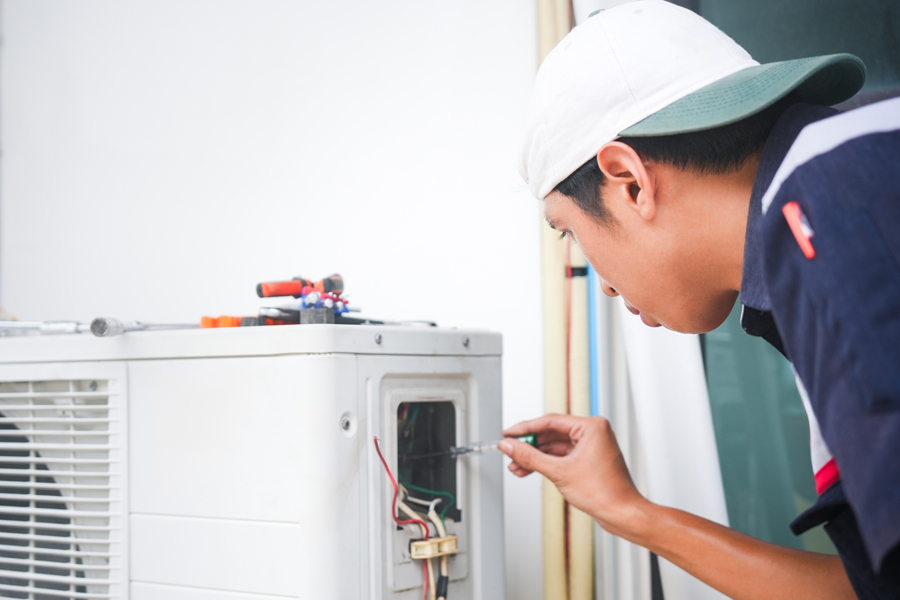 Technician repairing furnace with a screwdriver